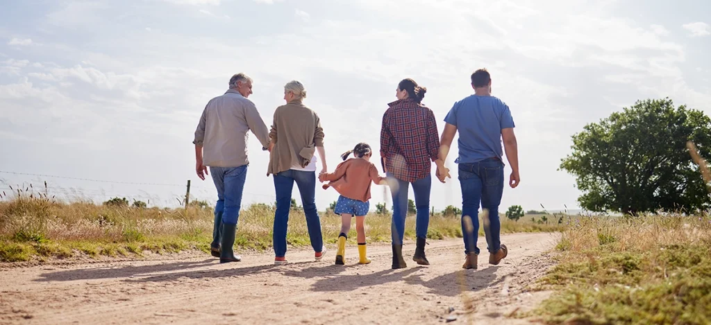 Multi-generational farm family walking down a dirt path of a farm