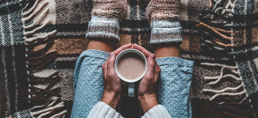 Woman holding coffee in lap with fuzzy socks