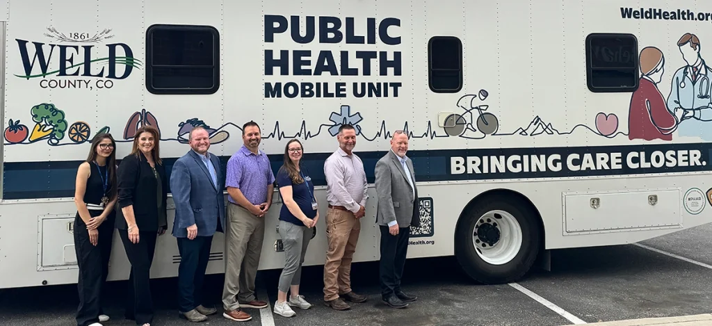 Group of Weld community members in front of the Weld County Public Health Mobile Unit.